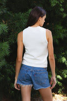 Woman wearing LIBBY American flag sweater knit tank featuring soft breathable 100% cotton sweater knit fabric, clean fitted silhouette, classic crew neckline, sleeveless design, American flag knit graphic across the front, ribbed trim along the neckline and armholes, and ribbed hem for a structured finish.