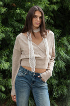 Woman wearing ELIA embroidered lace thin scarf featuring delicate sheer crochet lace fabric, intricate diamond pattern embroidery, soft textured dotted embroidery details, narrow skinny scarf silhouette, scalloped lace trim along both edges, and long tapered ends for a romantic vintage inspired look.