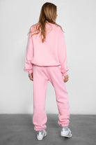 Person wearing a pink tracksuit against a plain background
