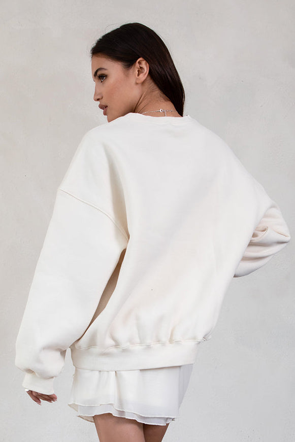 Person wearing a ecru sweatshirt and shorts set against a plain background