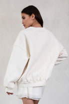 Person wearing a ecru sweatshirt and shorts set against a plain background