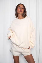 Person wearing a cream-colored oversized sweater and shorts set against a white background