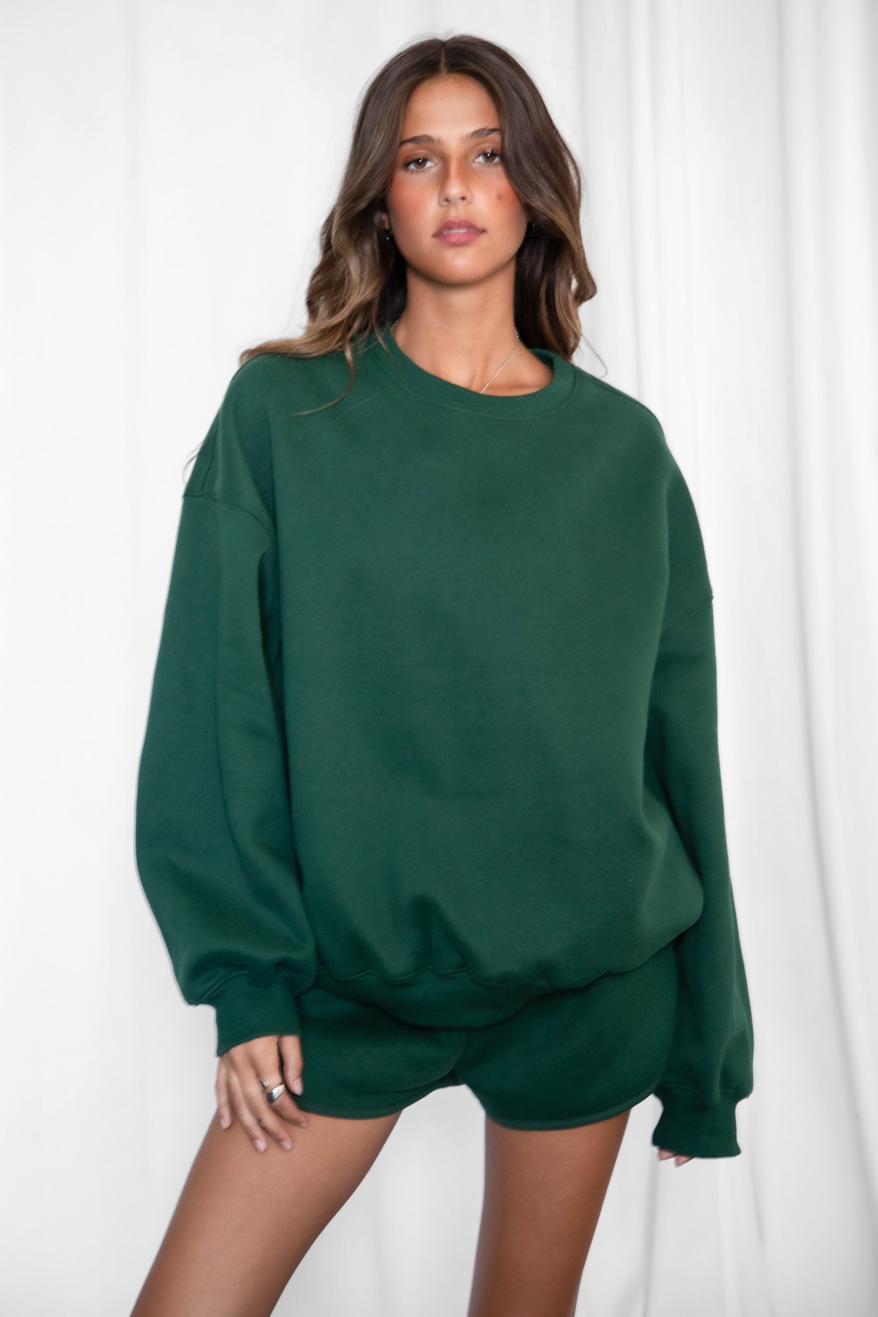 Woman wearing a green sweatshirt and shorts set against a white background