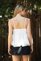 Woman wearing TIC TOC TH31010 CYRUS crinkle gauze cami top featuring a plunging V-neckline, adjustable shoulder straps, tiered babydoll silhouette, asymmetrical raw-cut hem, and soft lightweight cotton gauze texture for a western-inspired summer look.