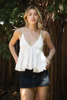 Woman wearing TIC TOC TH31010 CYRUS crinkle gauze cami top featuring a plunging V-neckline, adjustable shoulder straps, tiered babydoll silhouette, asymmetrical raw-cut hem, and soft lightweight cotton gauze texture for a western-inspired summer look.