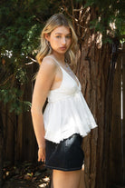 Woman wearing TIC TOC TH31010 CYRUS crinkle gauze cami top featuring a plunging V-neckline, adjustable shoulder straps, tiered babydoll silhouette, asymmetrical raw-cut hem, and soft lightweight cotton gauze texture for a western-inspired summer look.