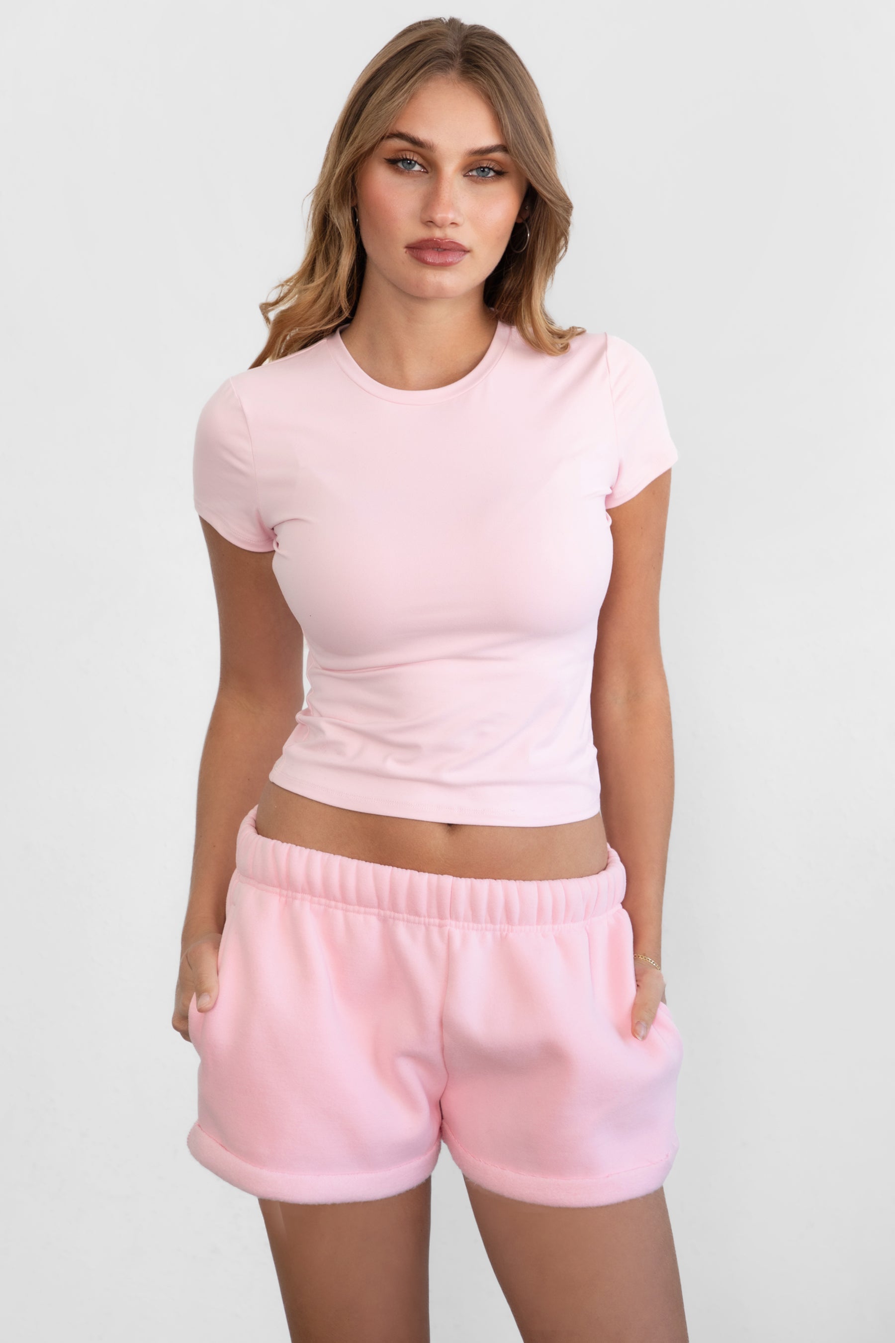 Woman wearing TIC TOC TH31439BA-ARIET ARIET brushed poly short sleeve top featuring a high round neckline, short cap sleeves, smooth bodyhugging stretch fabric, and a clean minimal silhouette, styled with matching fleece joggers as a coordinated lounge set.