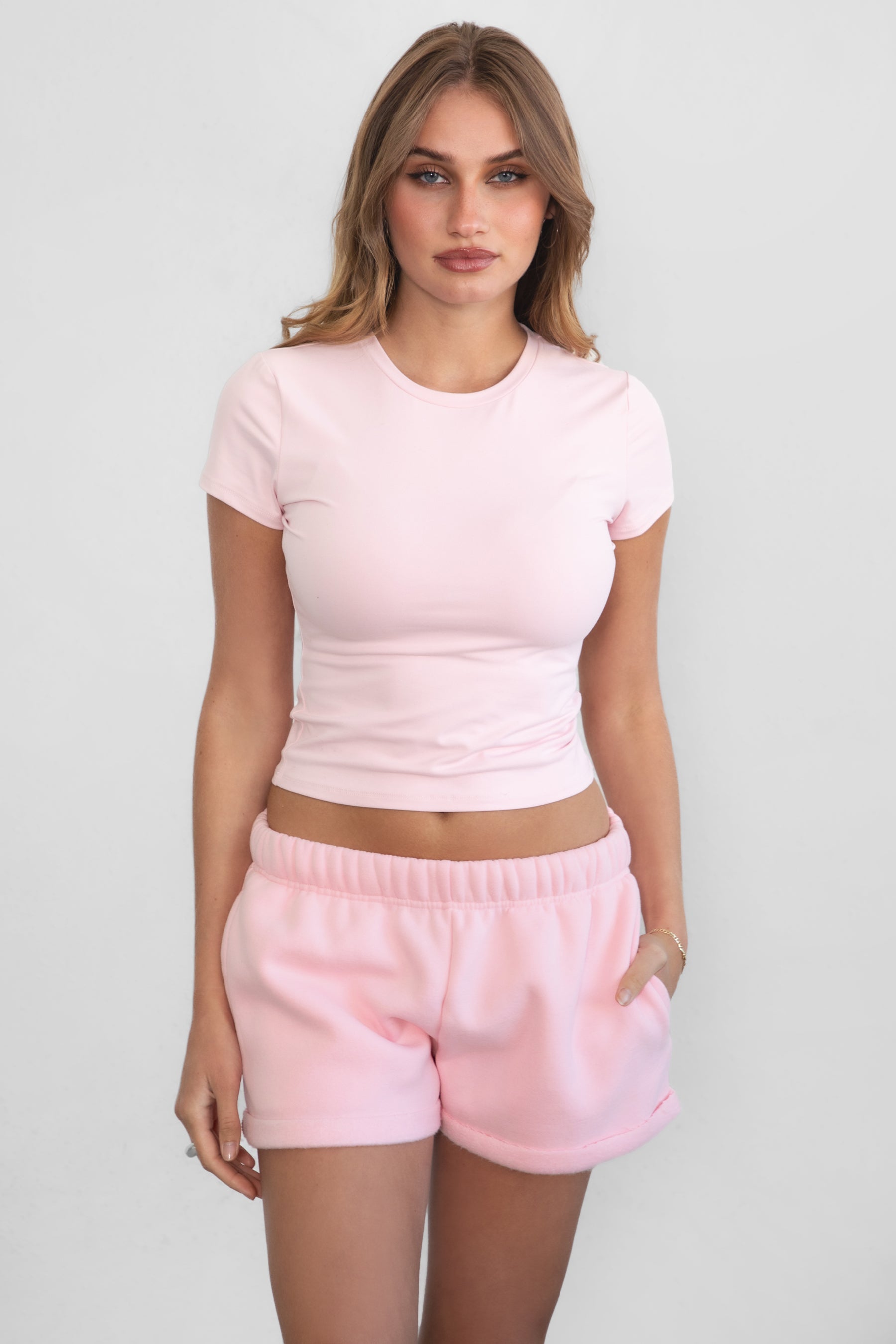 Woman wearing TIC TOC TH31439BA-ARIET ARIET brushed poly short sleeve top featuring a high round neckline, short cap sleeves, smooth bodyhugging stretch fabric, and a clean minimal silhouette, styled with matching fleece joggers as a coordinated lounge set.