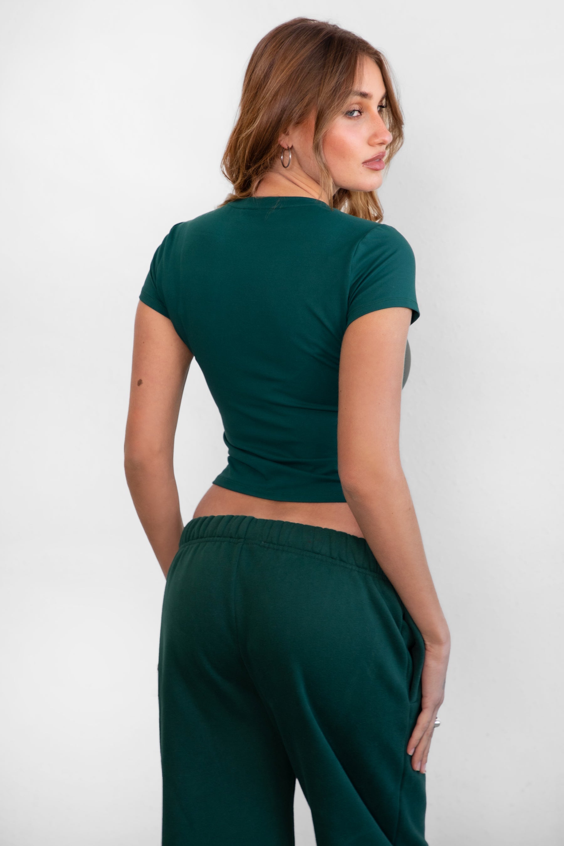 Woman wearing TIC TOC TH31439BA-ARIET ARIET brushed poly short sleeve top featuring a high round neckline, short cap sleeves, smooth bodyhugging stretch fabric, and a clean minimal silhouette, styled with matching fleece joggers as a coordinated lounge set.