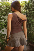Woman wearing a brown top and skirt standing in a garden setting