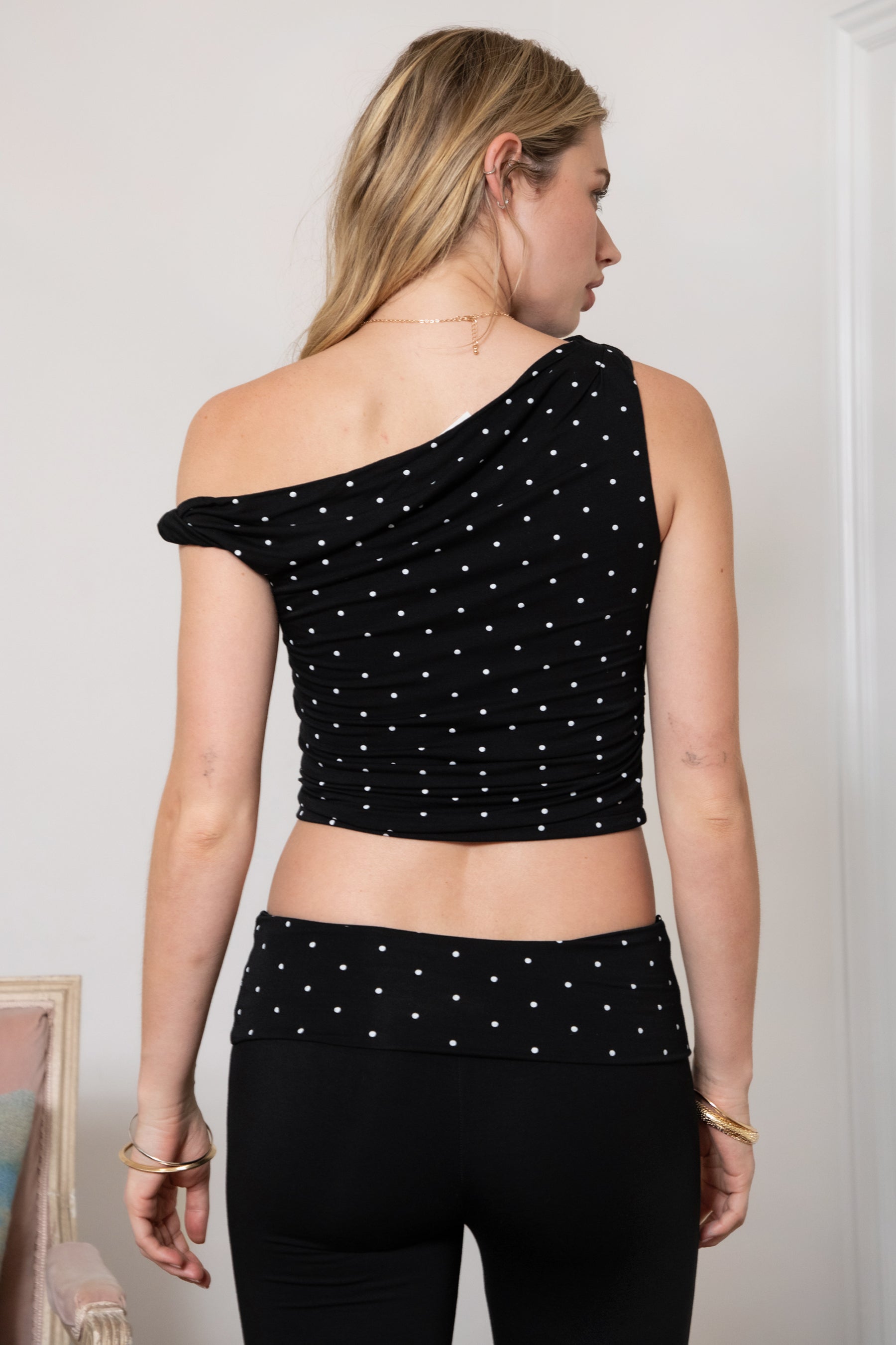 Woman wearing TIC TOC TH31776-JAIME-TP JAIME lightweight one shoulder polka dot top featuring a soft micro polka dot stretch fabric, asymmetrical off-the-shoulder neckline, twist strap detail, side ruching, and a slim hip-length silhouette for a chic day-to-night look.