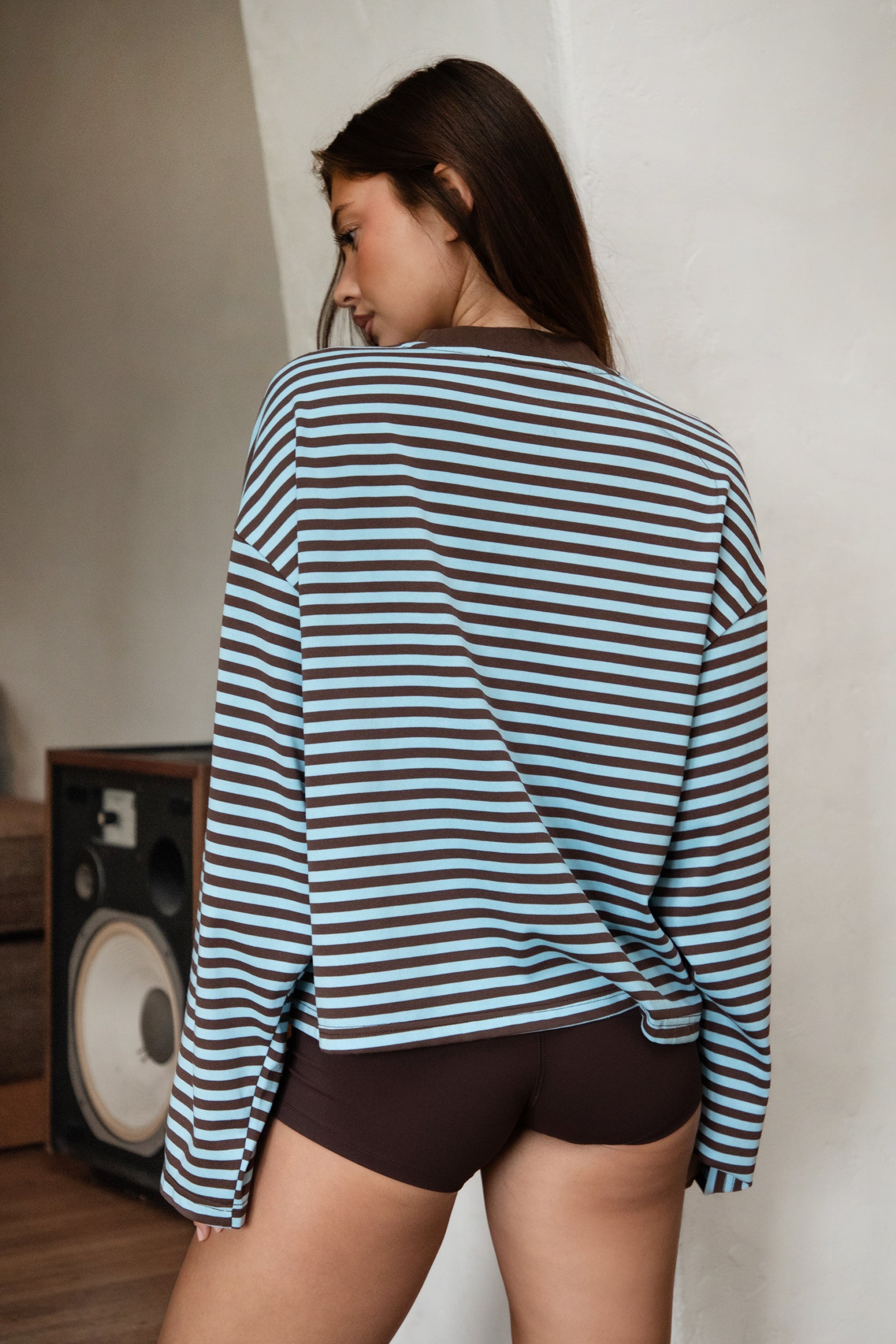 Woman wearing TIC TOC TH31849 MARLOWE striped long sleeve top with a classic crew neckline, relaxed semi-oversized fit, easy drop shoulders, and soft horizontal stripes paired with dark denim jeans in a casual outdoor street setting.
