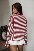 Woman wearing TIC TOC TH31849 MARLOWE striped long sleeve top with a classic crew neckline, relaxed semi-oversized fit, easy drop shoulders, and soft horizontal stripes paired with dark denim jeans in a casual outdoor street setting.