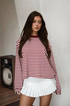 Woman wearing TIC TOC TH31849 MARLOWE striped long sleeve top with a classic crew neckline, relaxed semi-oversized fit, easy drop shoulders, and soft horizontal stripes paired with dark denim jeans in a casual outdoor street setting.