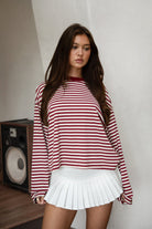Woman wearing TIC TOC TH31849 MARLOWE striped long sleeve top with a classic crew neckline, relaxed semi-oversized fit, easy drop shoulders, and soft horizontal stripes paired with dark denim jeans in a casual outdoor street setting.