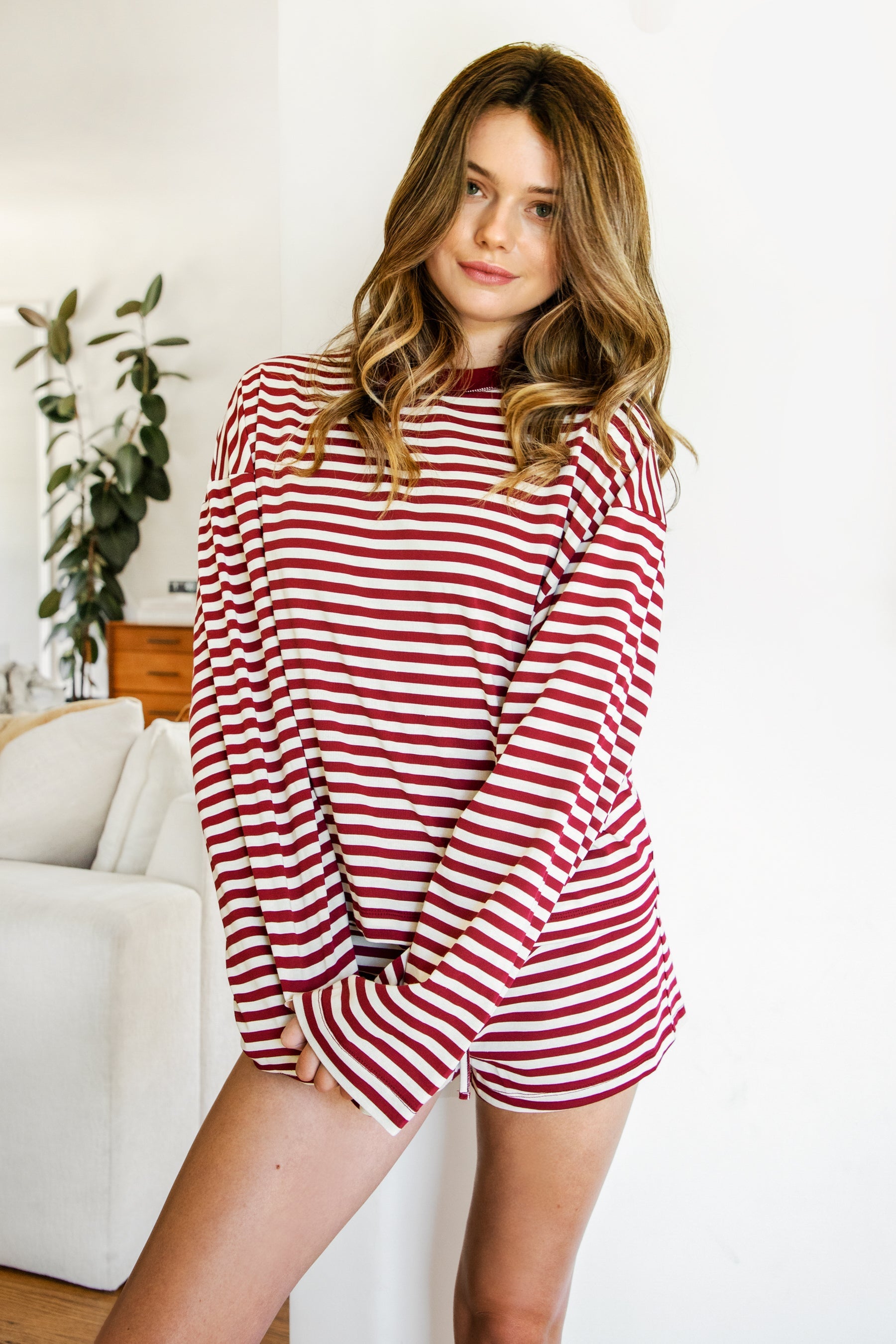 Woman wearing TIC TOC TH31849 MARLOWE striped long sleeve top with a classic crew neckline, relaxed semi-oversized fit, easy drop shoulders, and soft horizontal stripes paired with dark denim jeans in a casual outdoor street setting.