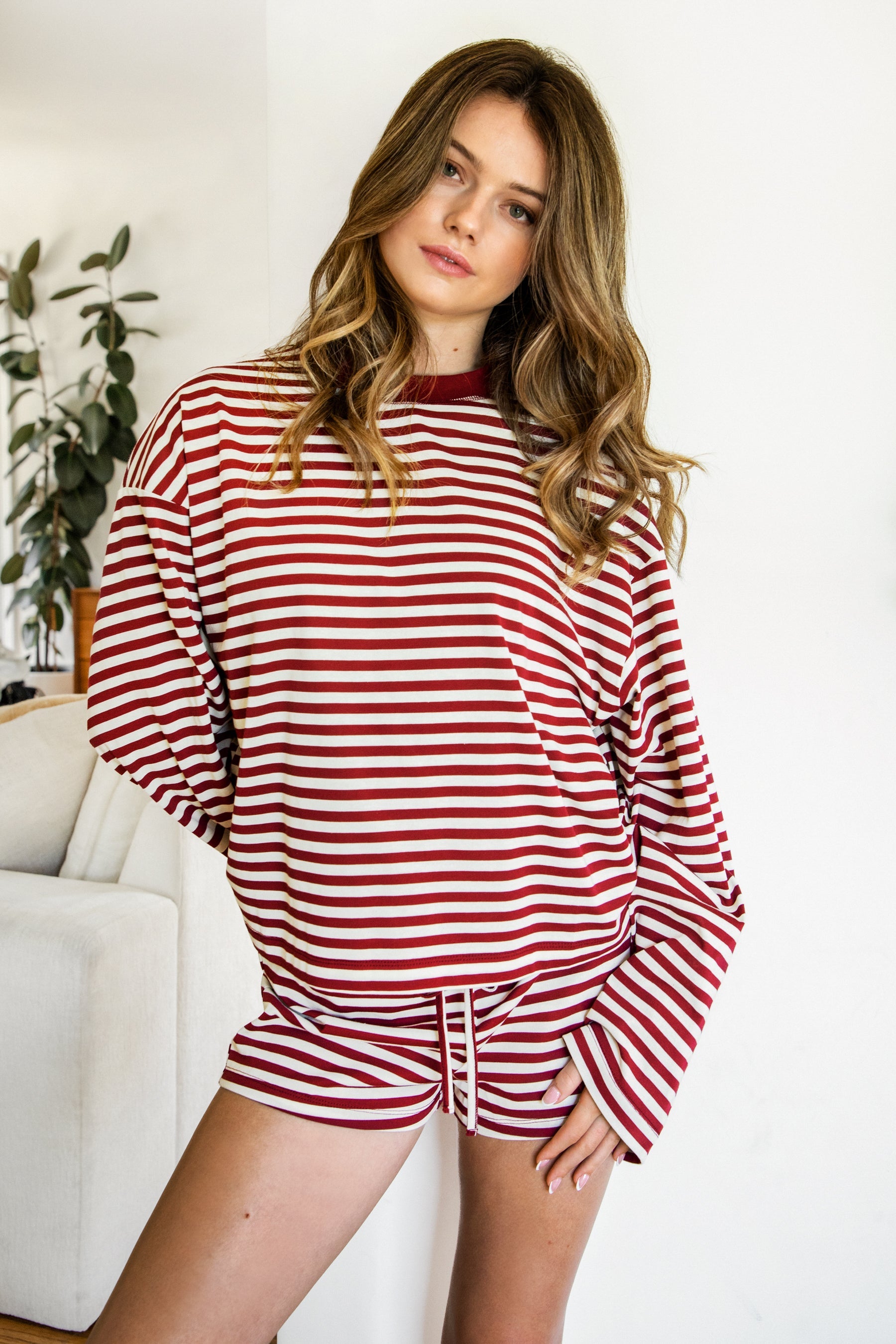 Woman wearing TIC TOC TH31849 MARLOWE striped long sleeve top with a classic crew neckline, relaxed semi-oversized fit, easy drop shoulders, and soft horizontal stripes paired with dark denim jeans in a casual outdoor street setting.