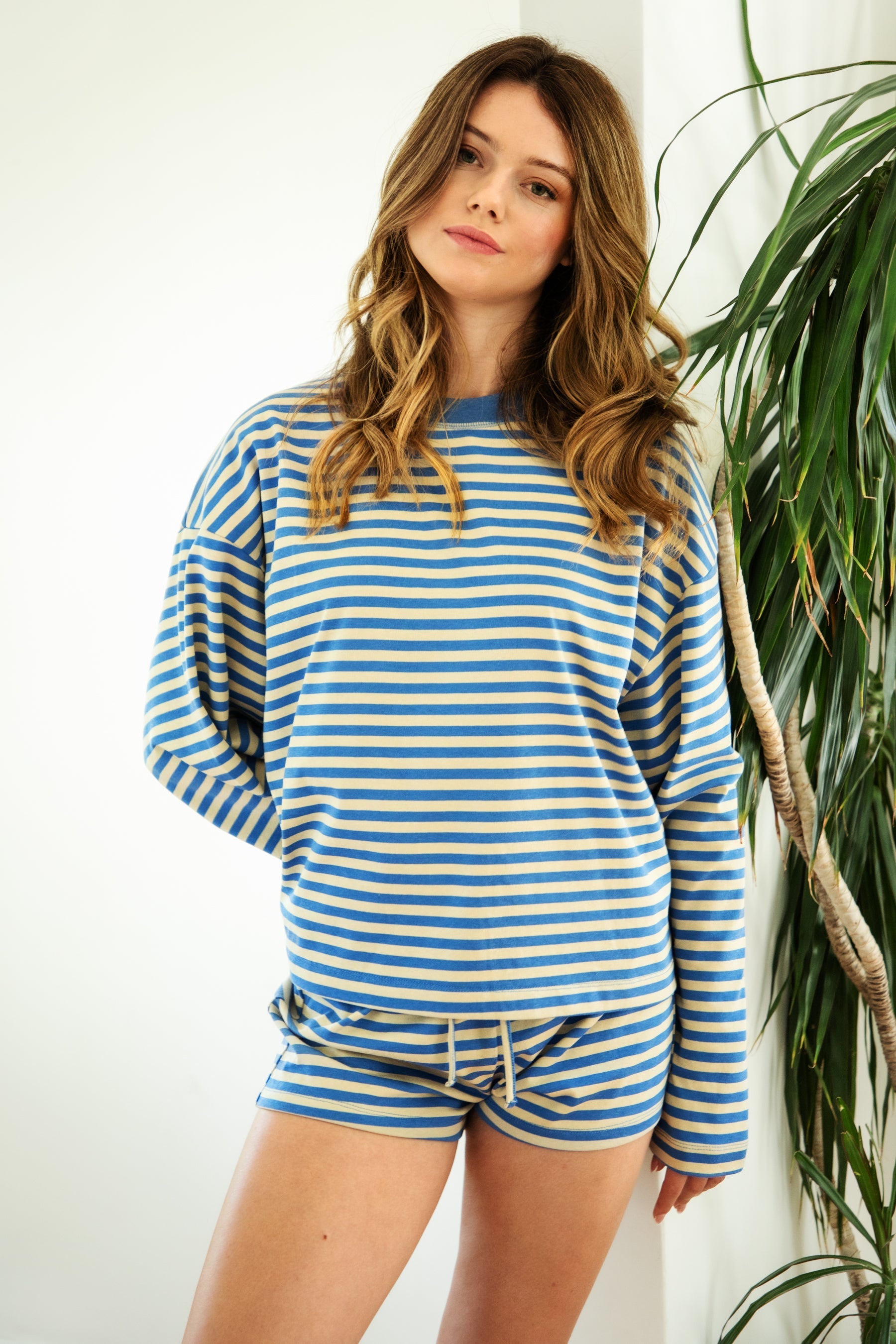 Woman wearing TIC TOC TH31849 MARLOWE striped long sleeve top with a classic crew neckline, relaxed semi-oversized fit, easy drop shoulders, and soft horizontal stripes paired with dark denim jeans in a casual outdoor street setting.