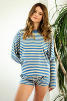 Woman wearing TIC TOC TH31849 MARLOWE striped long sleeve top with a classic crew neckline, relaxed semi-oversized fit, easy drop shoulders, and soft horizontal stripes paired with dark denim jeans in a casual outdoor street setting.