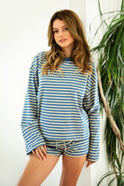 Woman wearing TIC TOC TH31849 MARLOWE striped long sleeve top with a classic crew neckline, relaxed semi-oversized fit, easy drop shoulders, and soft horizontal stripes paired with dark denim jeans in a casual outdoor street setting.indoors.