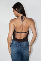 Woman wearing TIC TOC TH31911-TERAYA TERAYA open back halter neck top featuring an adjustable halter neckline, eyelet front button detail, deep asymmetrical front cutout, soft stretch jersey fabric, slim feminine fit, and open cowl back silhouette, styled with low-rise bottoms for a Y2K-inspired night-out and festival look