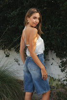 Woman wearing TIC TOC TH31911-TERAYA TERAYA open back halter neck top featuring an adjustable halter neckline, eyelet front button detail, deep asymmetrical front cutout, soft stretch jersey fabric, slim feminine fit, and open cowl back silhouette, styled with low-rise bottoms for a Y2K-inspired night-out and festival look