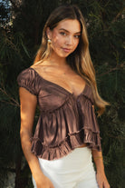 Woman wearing TIC TOC TH31912-AVELINE AVELINE V-neck boho lace trim babydoll top featuring a deep V-neckline with lace trim, mini puff sleeves with soft elastic cuffs, front button detail at the bodice, tiered babydoll silhouette with ruffle hem, and a smocked fitted back with adjustable bow tie in lightweight cotton voile, styled with denim for a soft boho western romantic everyday look