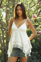 Woman wearing TIC TOC TH31975 MARIELLE tiered lace ruffle trim V-neck babydoll top featuring soft airy slub cotton fabric, a flattering babydoll silhouette, delicate lace trim at the neckline, adjustable spaghetti straps, and an asymmetrical tiered ruffle hem for a romantic warm weather look.