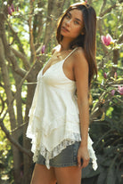 Woman wearing TIC TOC TH31975 MARIELLE tiered lace ruffle trim V-neck babydoll top featuring soft airy slub cotton fabric, a flattering babydoll silhouette, delicate lace trim at the neckline, adjustable spaghetti straps, and an asymmetrical tiered ruffle hem for a romantic warm weather look.