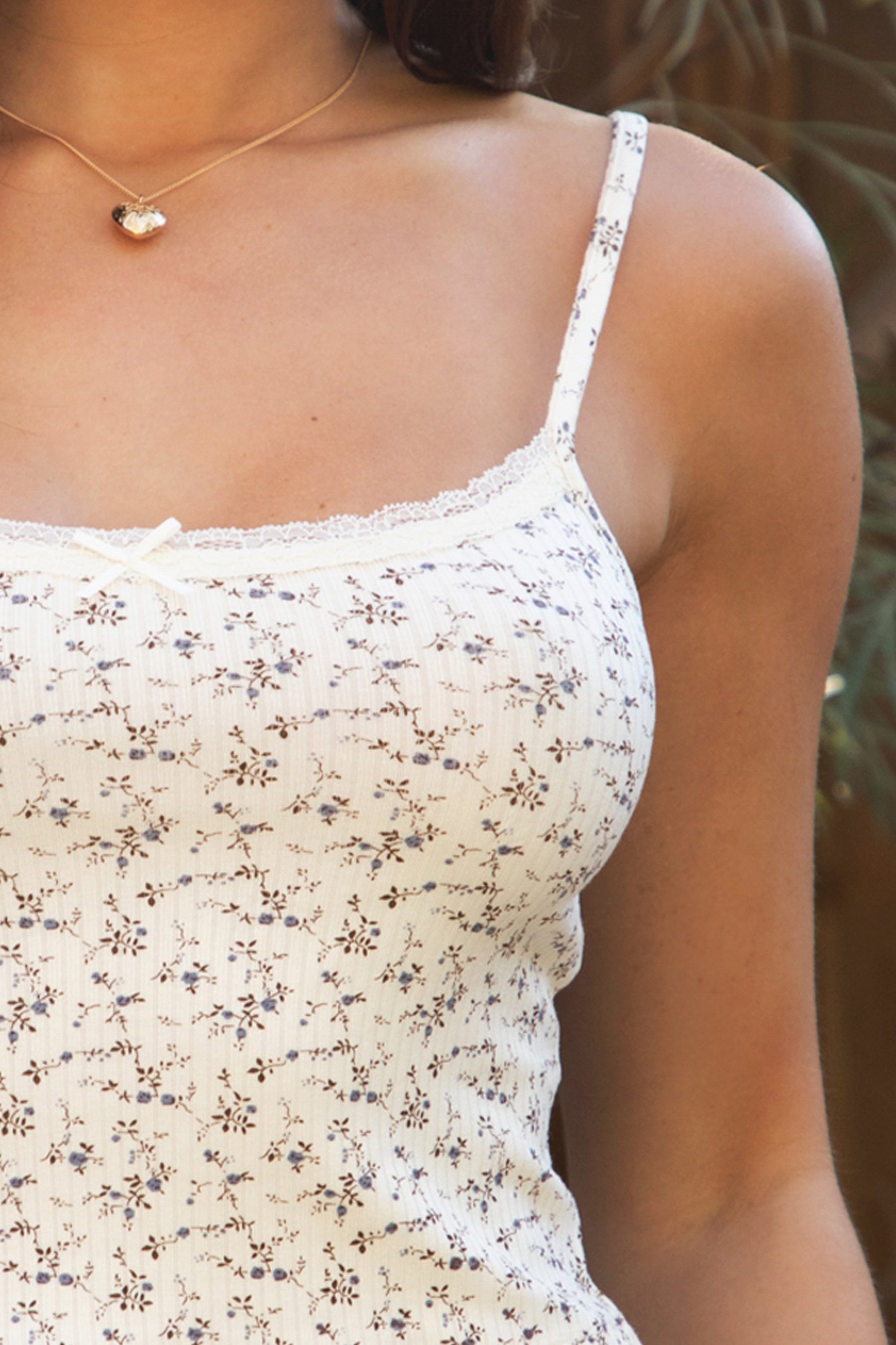 Woman wearing TIC TOC TH31984-LYNN-CAM LYNN floral pointelle slim cropped cami top featuring a slim cropped camisole silhouette with adjustable straps, exposed lace trim along the neckline and back, ribbed floral pointelle texture, and soft airy stretch fabric, styled with relaxed lounge pants for a feminine everyday comfort look.