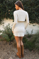 Woman wearing TIC TOC TH31985-LYNN-CC LYNN floral pointelle print long sleeve bolero top featuring a wide boat neckline with front cutout, single front buckle closure, long fitted sleeves, cropped bolero length, and ribbed floral pointelle fabric with a soft airy stretch figure-hugging fit, styled layered over a matching floral pointelle cami and lounge pants for a feminine cozy set.