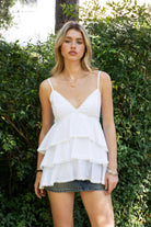 Woman wearing TIC TOC TH32062 GLARA tiered ruffle babydoll top featuring a plunging V-neckline with lace trim, tiered ruffle layers with lace edge detail, adjustable thin spaghetti straps, and a soft flowy babydoll silhouette in lightweight cotton poplin for a feminine western summer look.