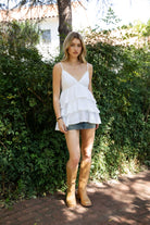 Woman wearing TIC TOC TH32062 GLARA tiered ruffle babydoll top featuring a plunging V-neckline with lace trim, tiered ruffle layers with lace edge detail, adjustable thin spaghetti straps, and a soft flowy babydoll silhouette in lightweight cotton poplin for a feminine western summer look.