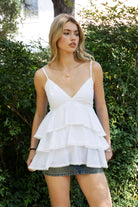 Woman wearing TIC TOC TH32062 GLARA tiered ruffle babydoll top featuring a plunging V-neckline with lace trim, tiered ruffle layers with lace edge detail, adjustable thin spaghetti straps, and a soft flowy babydoll silhouette in lightweight cotton poplin for a feminine western summer look.