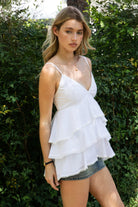 Woman wearing TIC TOC TH32062 GLARA tiered ruffle babydoll top featuring a plunging V-neckline with lace trim, tiered ruffle layers with lace edge detail, adjustable thin spaghetti straps, and a soft flowy babydoll silhouette in lightweight cotton poplin for a feminine western summer look.