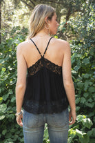 Woman wearing ROSA V-neck lace trim sheer babydoll cami top featuring a scalloped lace neckline, adjustable spaghetti straps with Y-back design, sheer crinkle rayon fabric with airy drape, floral lace panels at the bust and back, and a flowy silhouette with lace trim hem.