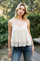 Woman wearing ROSA V-neck lace trim sheer babydoll cami top featuring a scalloped lace neckline, adjustable spaghetti straps with Y-back design, sheer crinkle rayon fabric with airy drape, floral lace panels at the bust and back, and a flowy silhouette with lace trim hem.