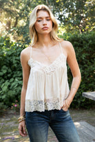 Woman wearing ROSA V-neck lace trim sheer babydoll cami top featuring a scalloped lace neckline, adjustable spaghetti straps with Y-back design, sheer crinkle rayon fabric with airy drape, floral lace panels at the bust and back, and a flowy silhouette with lace trim hem.