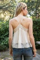 Woman wearing ROSA V-neck lace trim sheer babydoll cami top featuring a scalloped lace neckline, adjustable spaghetti straps with Y-back design, sheer crinkle rayon fabric with airy drape, floral lace panels at the bust and back, and a flowy silhouette with lace trim hem.