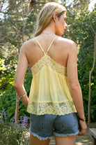 Woman wearing ROSA V-neck lace trim sheer babydoll cami top featuring a scalloped lace neckline, adjustable spaghetti straps with Y-back design, sheer crinkle rayon fabric with airy drape, floral lace panels at the bust and back, and a flowy silhouette with lace trim hem.