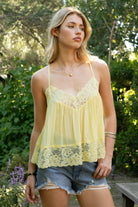 Woman wearing ROSA V-neck lace trim sheer babydoll cami top featuring a scalloped lace neckline, adjustable spaghetti straps with Y-back design, sheer crinkle rayon fabric with airy drape, floral lace panels at the bust and back, and a flowy silhouette with lace trim hem.