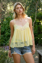 Woman wearing ROSA V-neck lace trim sheer babydoll cami top featuring a scalloped lace neckline, adjustable spaghetti straps with Y-back design, sheer crinkle rayon fabric with airy drape, floral lace panels at the bust and back, and a flowy silhouette with lace trim hem.