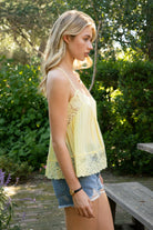 Woman wearing ROSA V-neck lace trim sheer babydoll cami top featuring a scalloped lace neckline, adjustable spaghetti straps with Y-back design, sheer crinkle rayon fabric with airy drape, floral lace panels at the bust and back, and a flowy silhouette with lace trim hem.