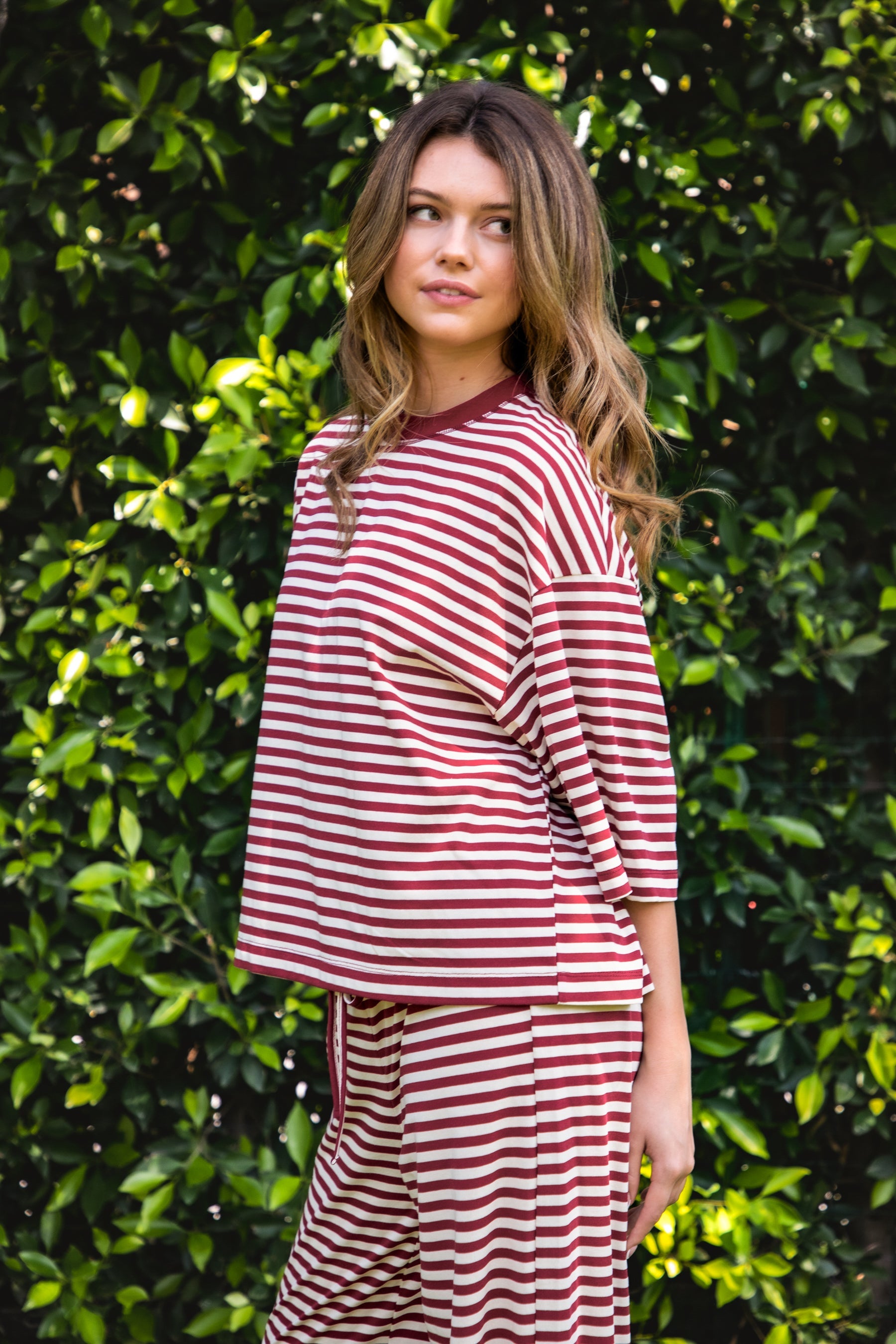 Woman wearing MARLOWE classic crewneck striped short sleeve top featuring a soft horizontal stripe pattern, relaxed semi oversized fit, drop shoulder short sleeves, lightweight stretch cotton blend, and clean straight hemline for casual lounge and coastal styling.