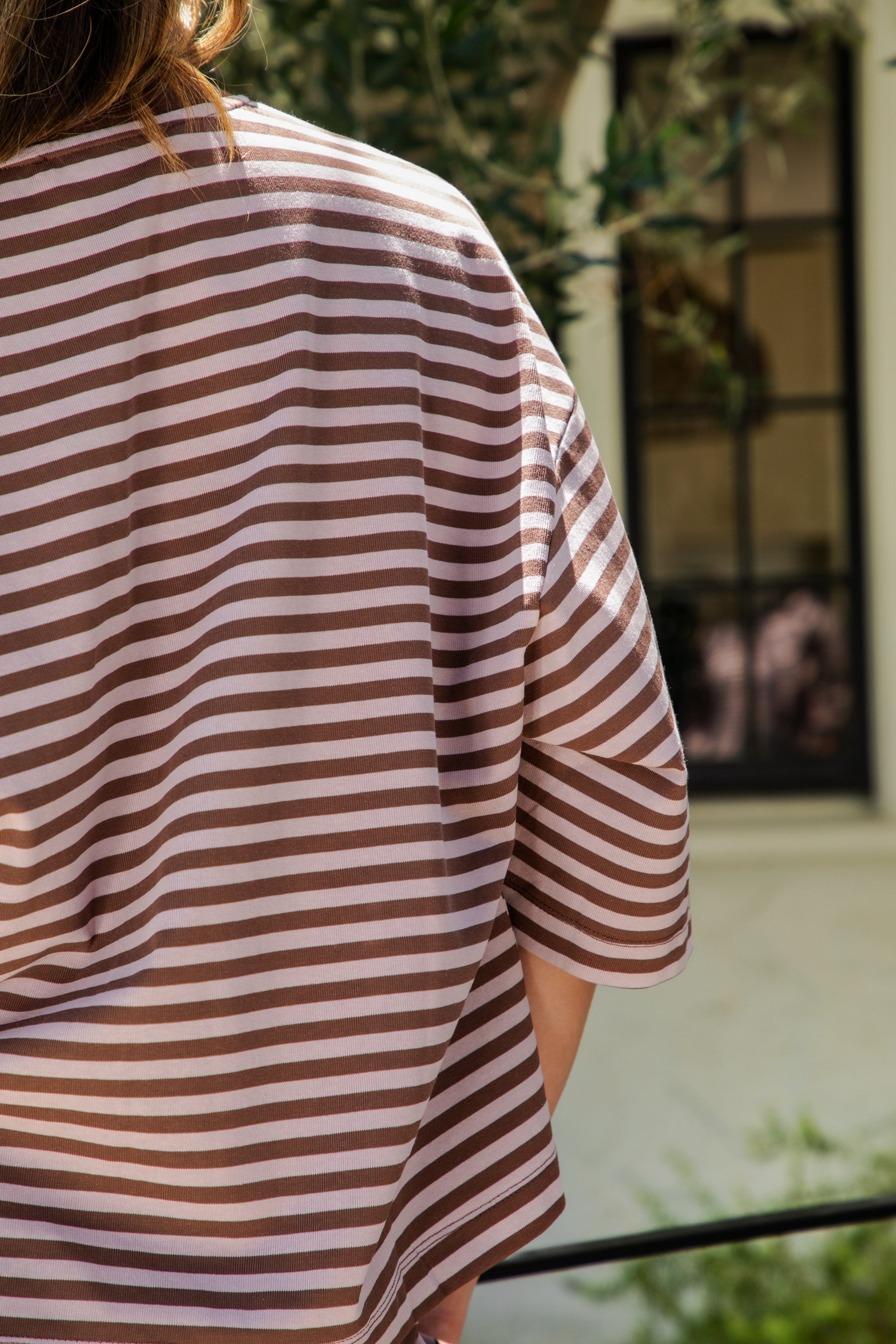 Woman wearing MARLOWE classic crewneck striped short sleeve top featuring a soft horizontal stripe pattern, relaxed semi oversized fit, drop shoulder short sleeves, lightweight stretch cotton blend, and clean straight hemline for casual lounge and coastal styling.