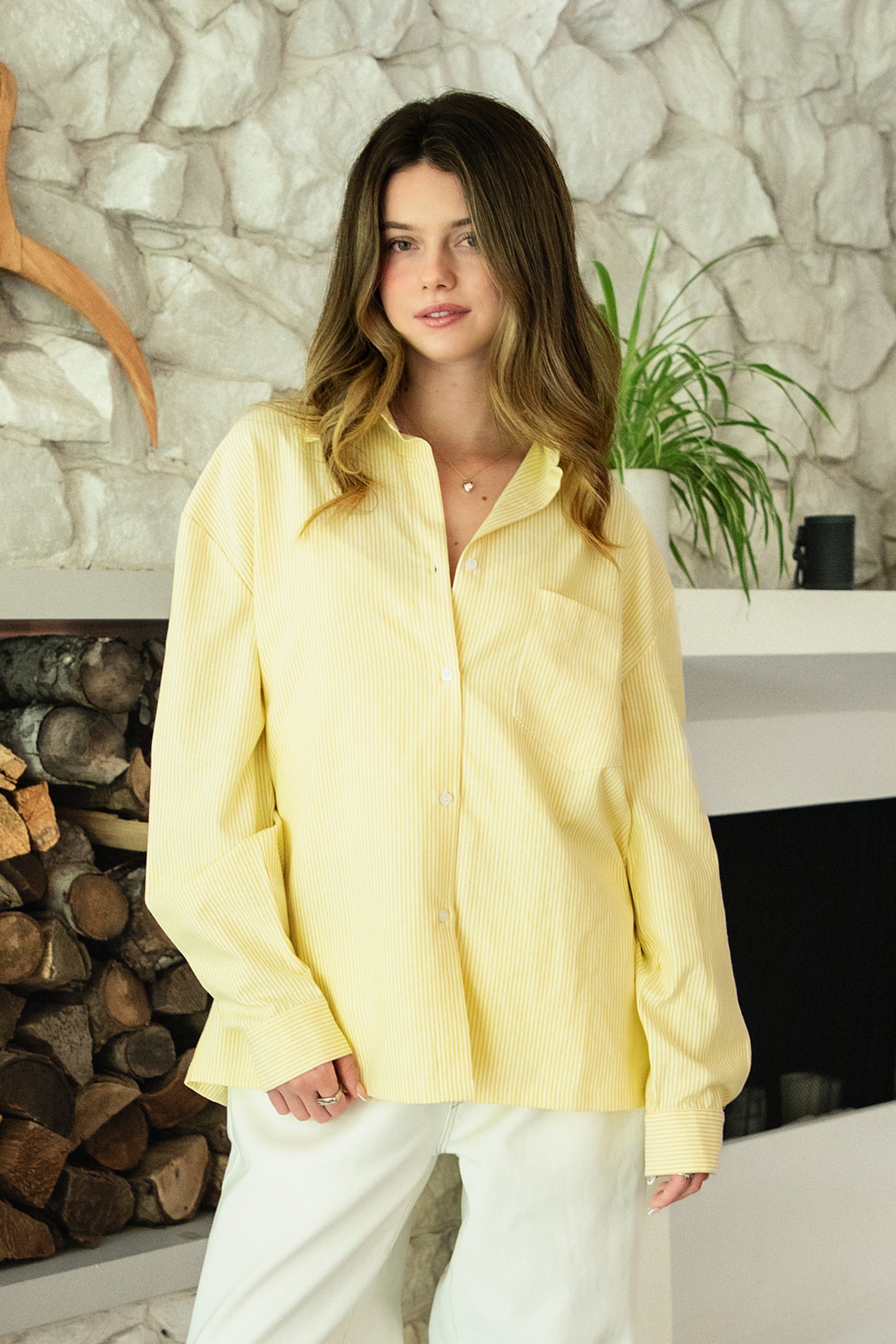 Woman wearing BLAIRE stripe oversized button down shirt featuring classic stripe oxford fabric, relaxed oversized silhouette, collared neckline, full front button closure, dropped shoulders, long sleeves with button cuffs, and functional chest pocket for effortless layering.
