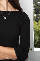 Woman wearing LUMA cotton rib three quarter sleeve boat neck top featuring soft cotton slub jersey, lightweight breathable feel, classic boat neckline, delicate picot trim, three quarter sleeves with matching cuff trim, picot trim hem, relaxed slim fit, and subtle curved hem.