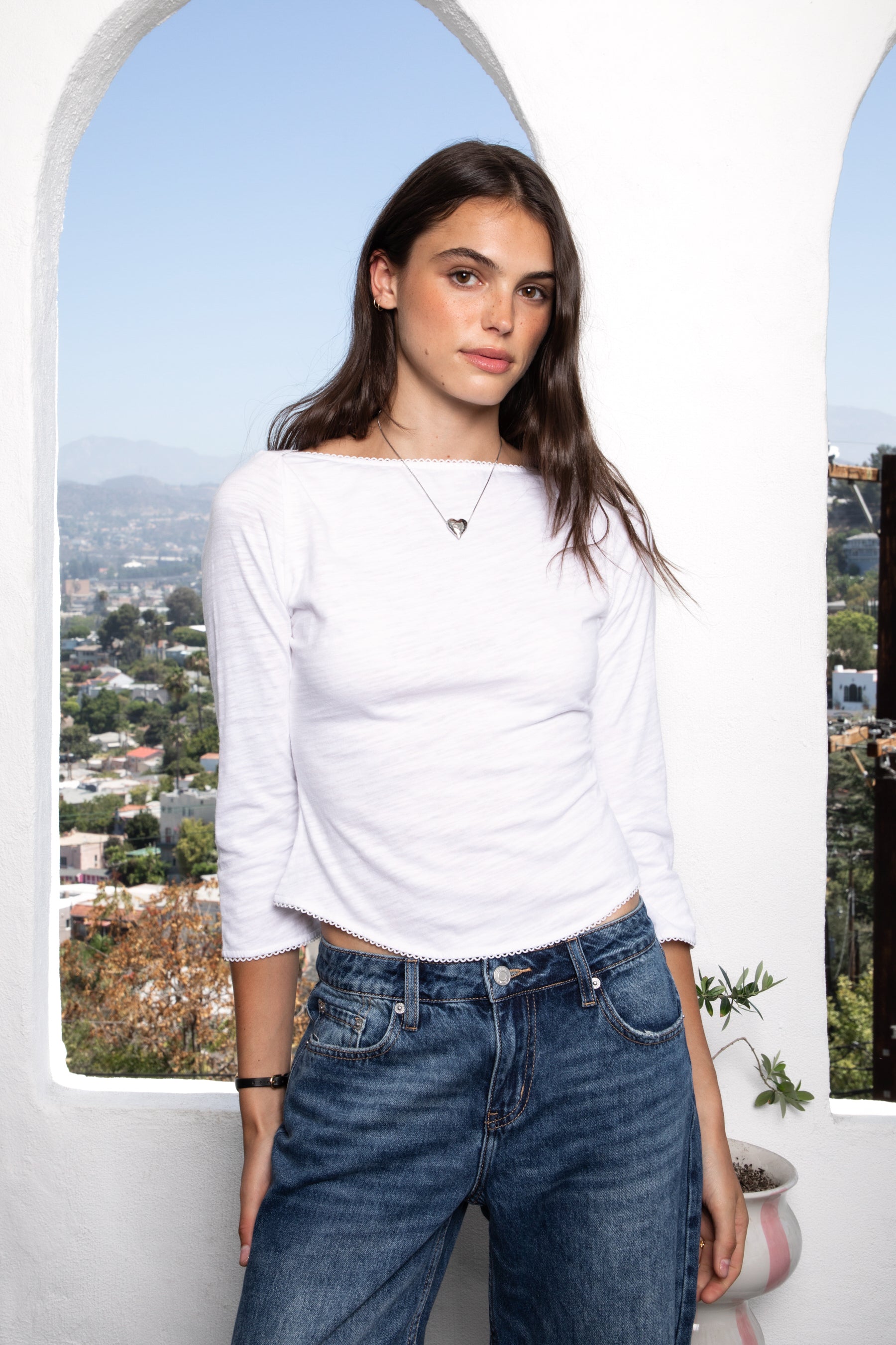Woman wearing LUMA cotton rib three quarter sleeve boat neck top featuring soft cotton slub jersey, lightweight breathable feel, classic boat neckline, delicate picot trim, three quarter sleeves with matching cuff trim, picot trim hem, relaxed slim fit, and subtle curved hem.