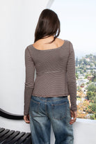 Woman wearing ELODY striped babydoll square neck henley peplum top featuring soft striped knit fabric, wide scoop neckline with contrast trim, henley inspired front placket with metal snap details, fitted bodice, empire waist seam, flared peplum hem, and long fitted sleeves.
