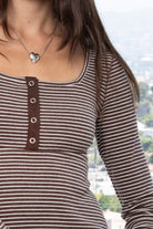 Woman wearing ELODY striped babydoll square neck henley peplum top featuring soft striped knit fabric, wide scoop neckline with contrast trim, henley inspired front placket with metal snap details, fitted bodice, empire waist seam, flared peplum hem, and long fitted sleeves.